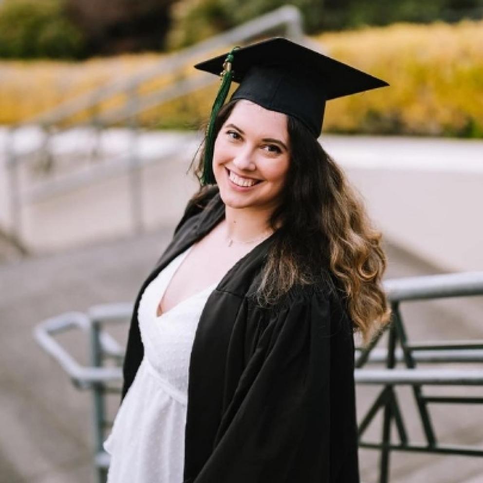 Student posing outside wearing cap and gown