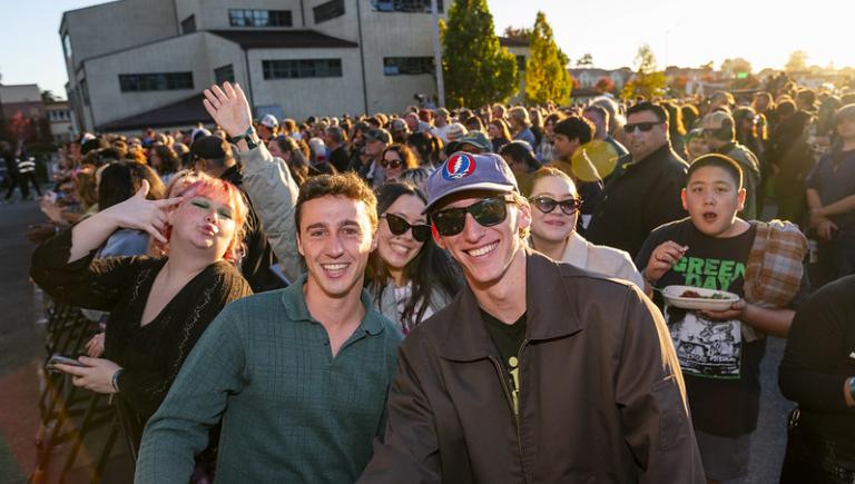 Two student smiling in front of a crowd at an outdoor concert.