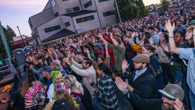 Large crowd clapping at arms in the air at a concert