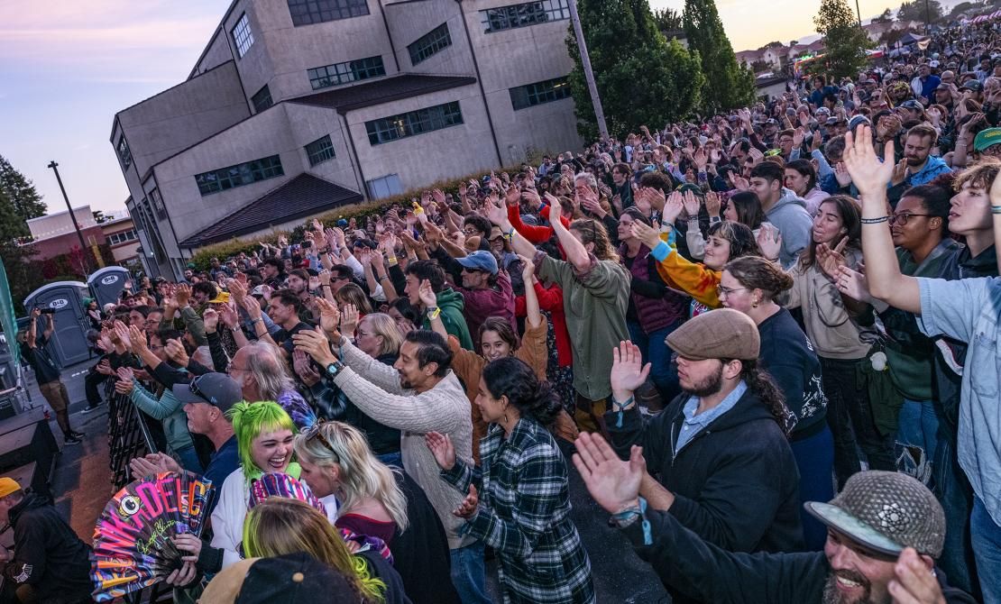 Large crowd clapping at arms in the air at a concert