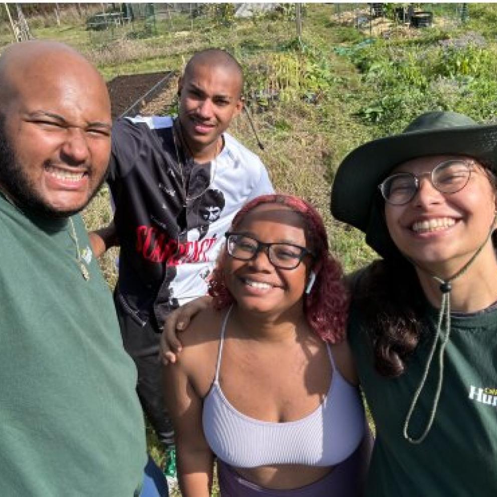 Image shows three team members squatting over to work in a garden bed at the Bayside Park Farm to the Black to the Land Program.
