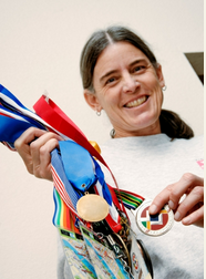 Photo of Sue Grigsby holding many medals