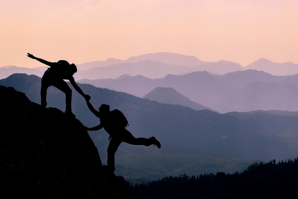 Person lending a helping hand to another in mountains