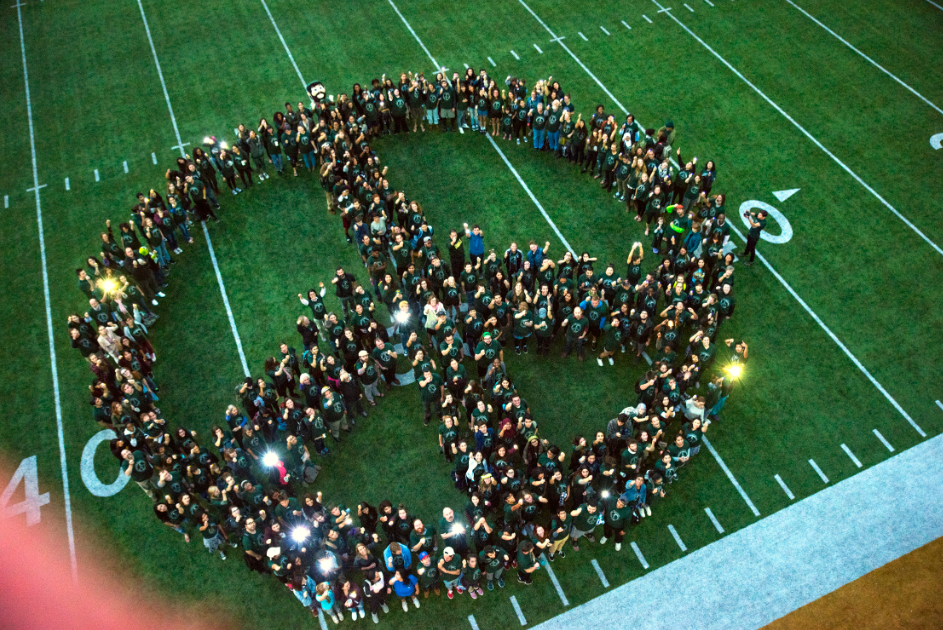 Students Standing in form of Peace Sign on football field