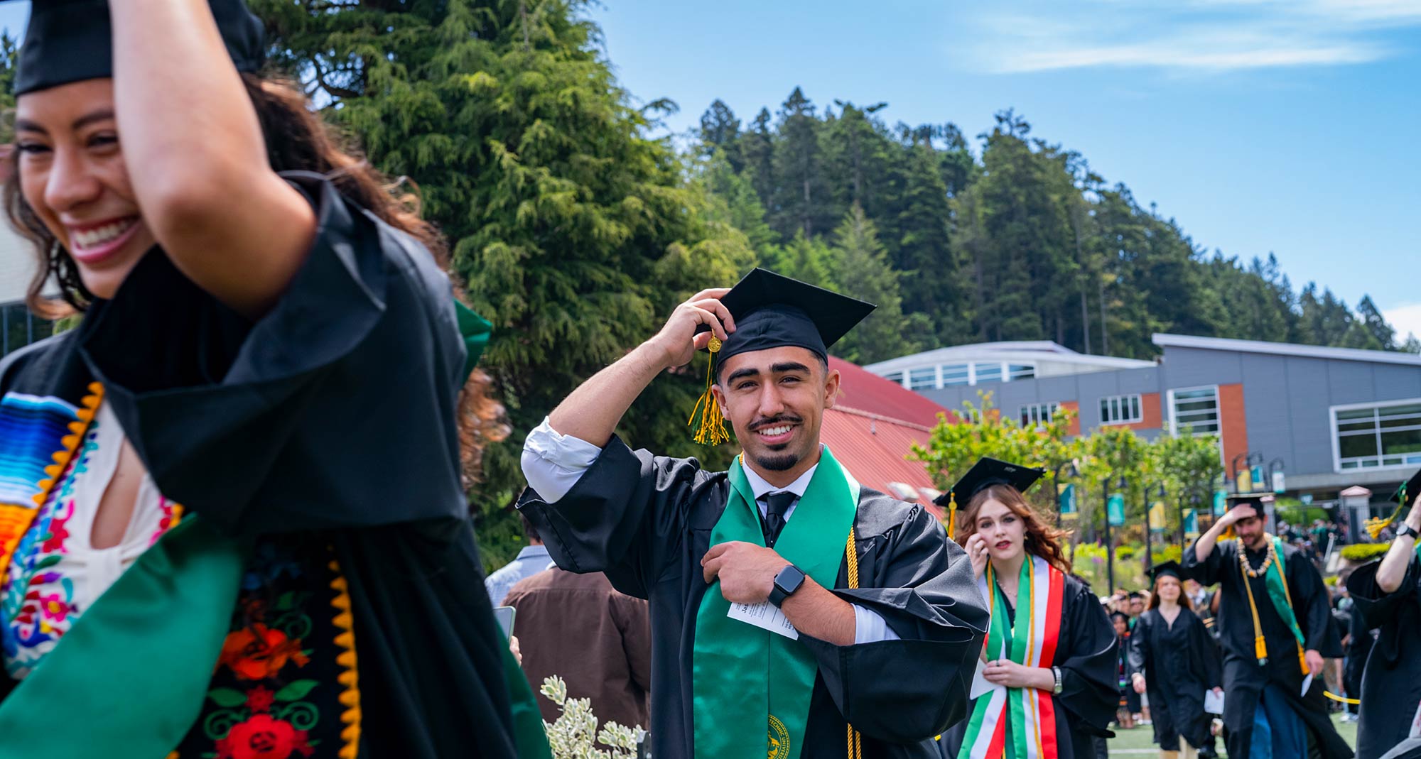 Graduates walking holding mortar boards in wind