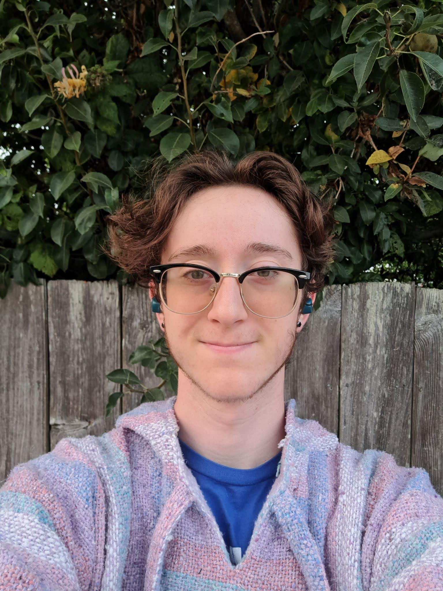 Chase smiles in front of a hedge.