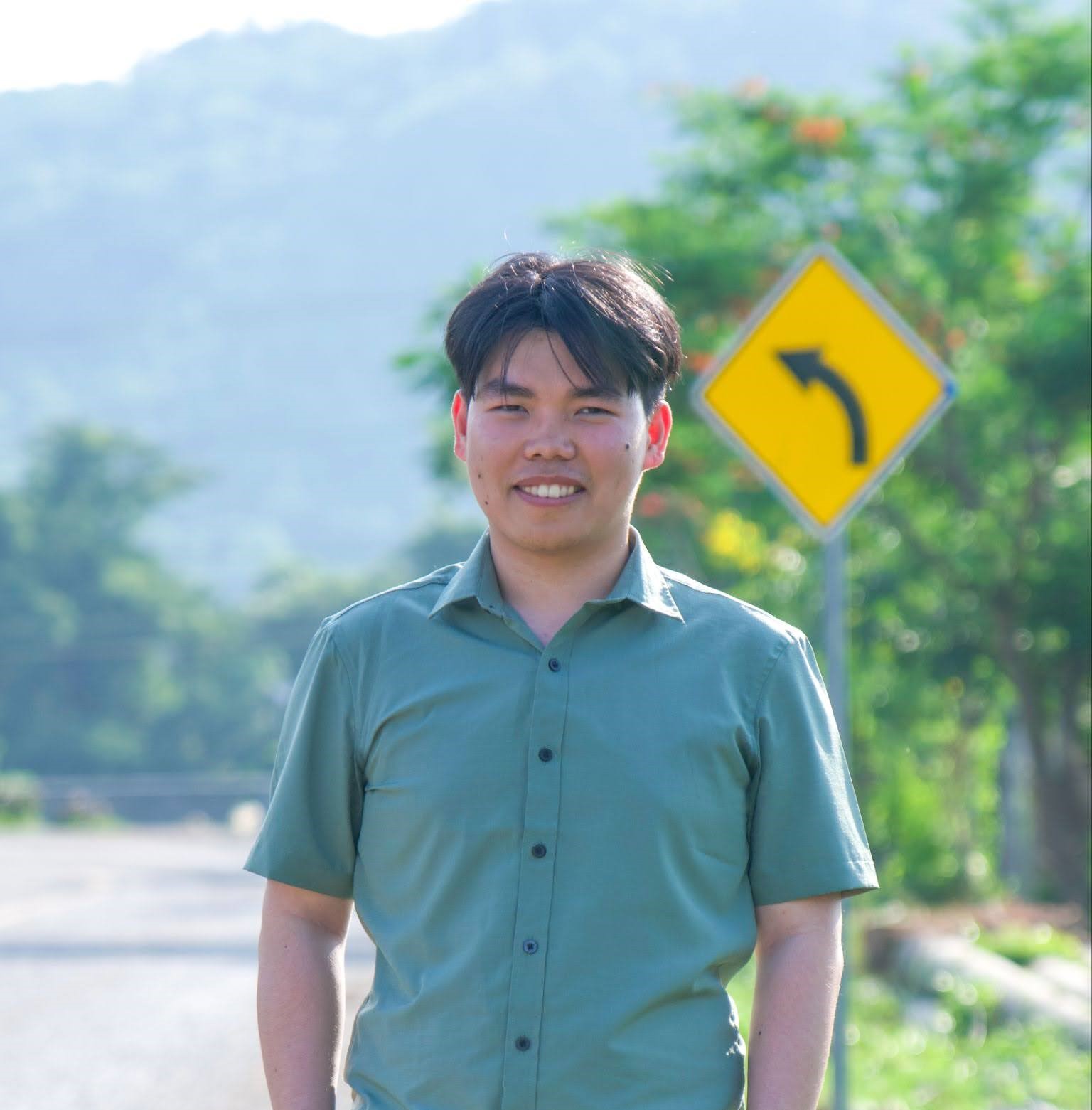 Heng stands on the side of the road, smiling.