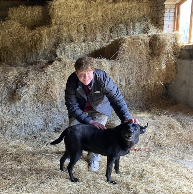 Jacoby stands and pets a dog.