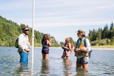 Research Scientists Mason London (left) and Emily Cooper (right) work with field technicians Priscilla Winters (center-left) and Ali Singh (center-right) to collect stream geomorphology data in the Mad River near Blue Lake, CA.