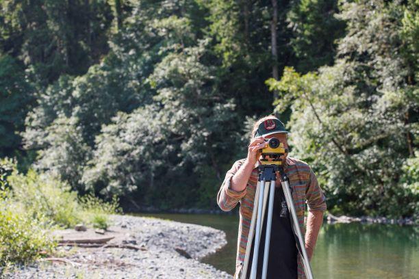 Field Technician Jesse Ritchie uses a surveyor's level to measure stream slope in the Mad River.