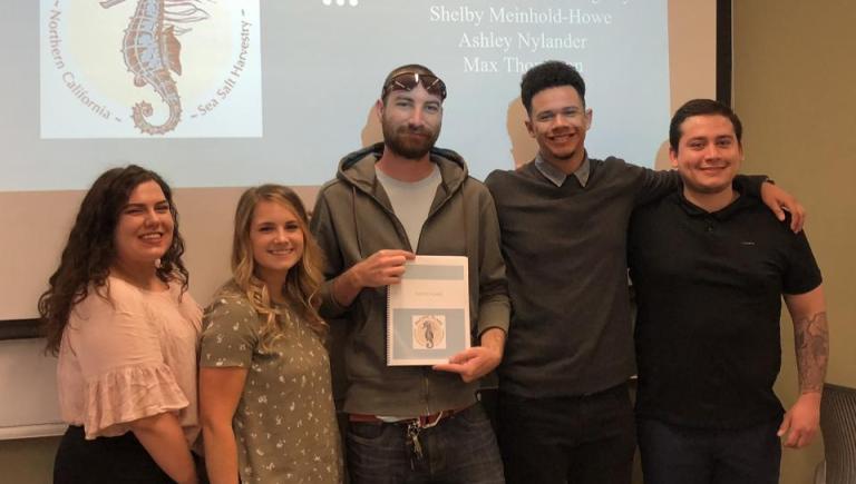 five people standing in front of a projector