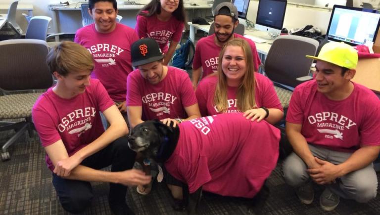 A group of students in matching red Osprey tshirts and a dog also wearing a tshirt