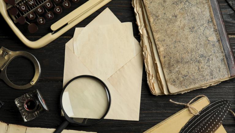 Detective's desktop with typewriter, magnifying glass, handcuffs, notebooks