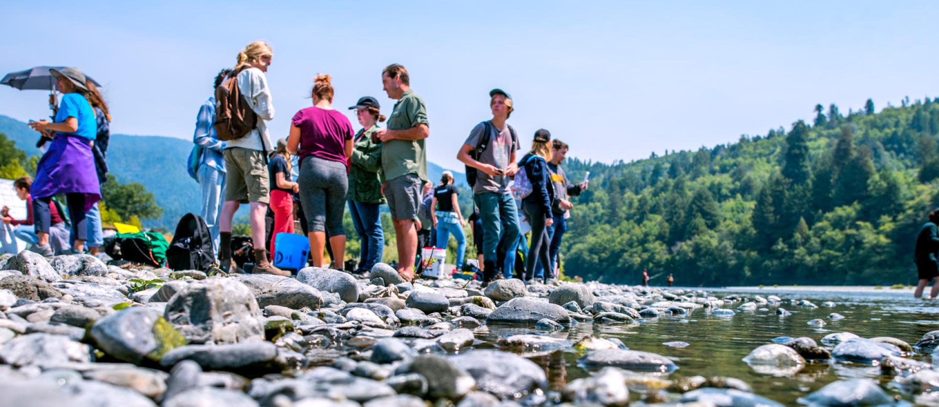 students standing on rocks by the river studying