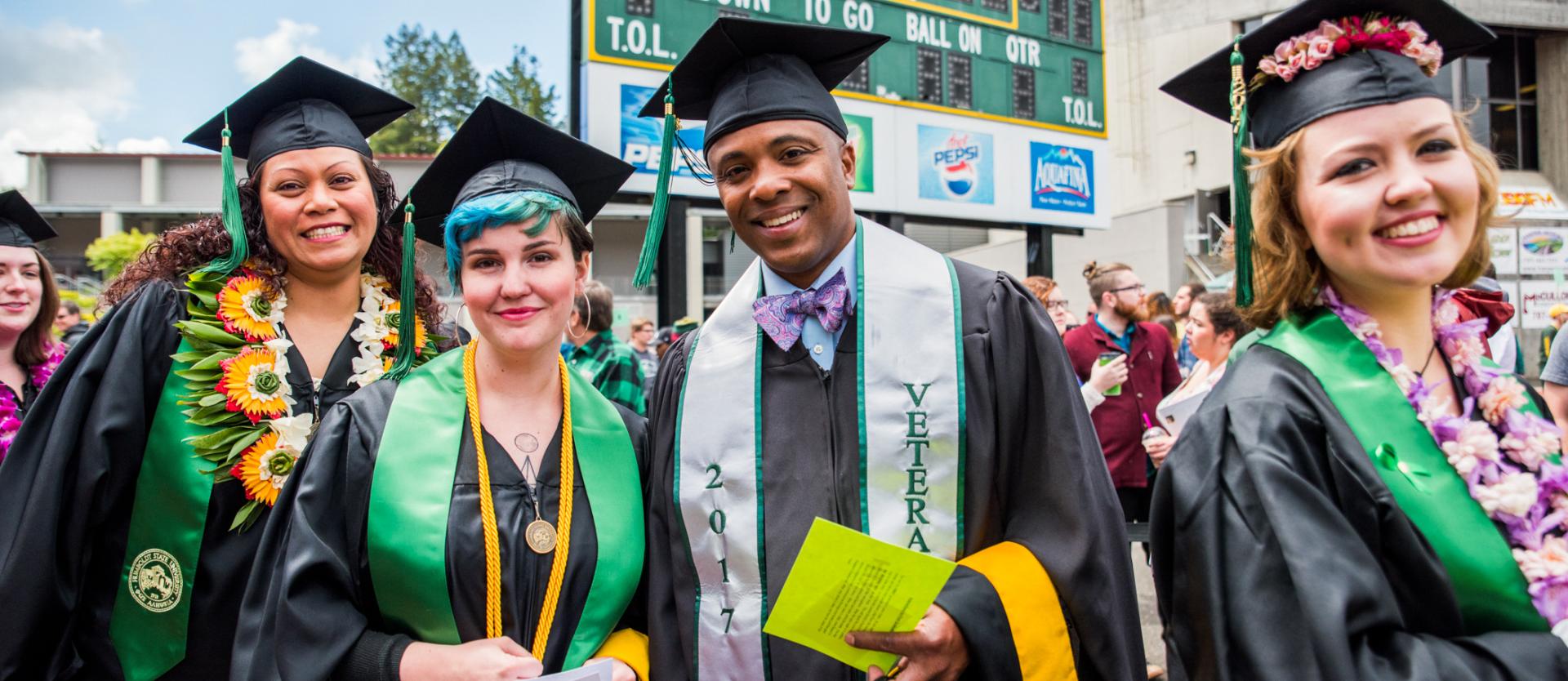 Four graduates in their gown and mortarboard hats