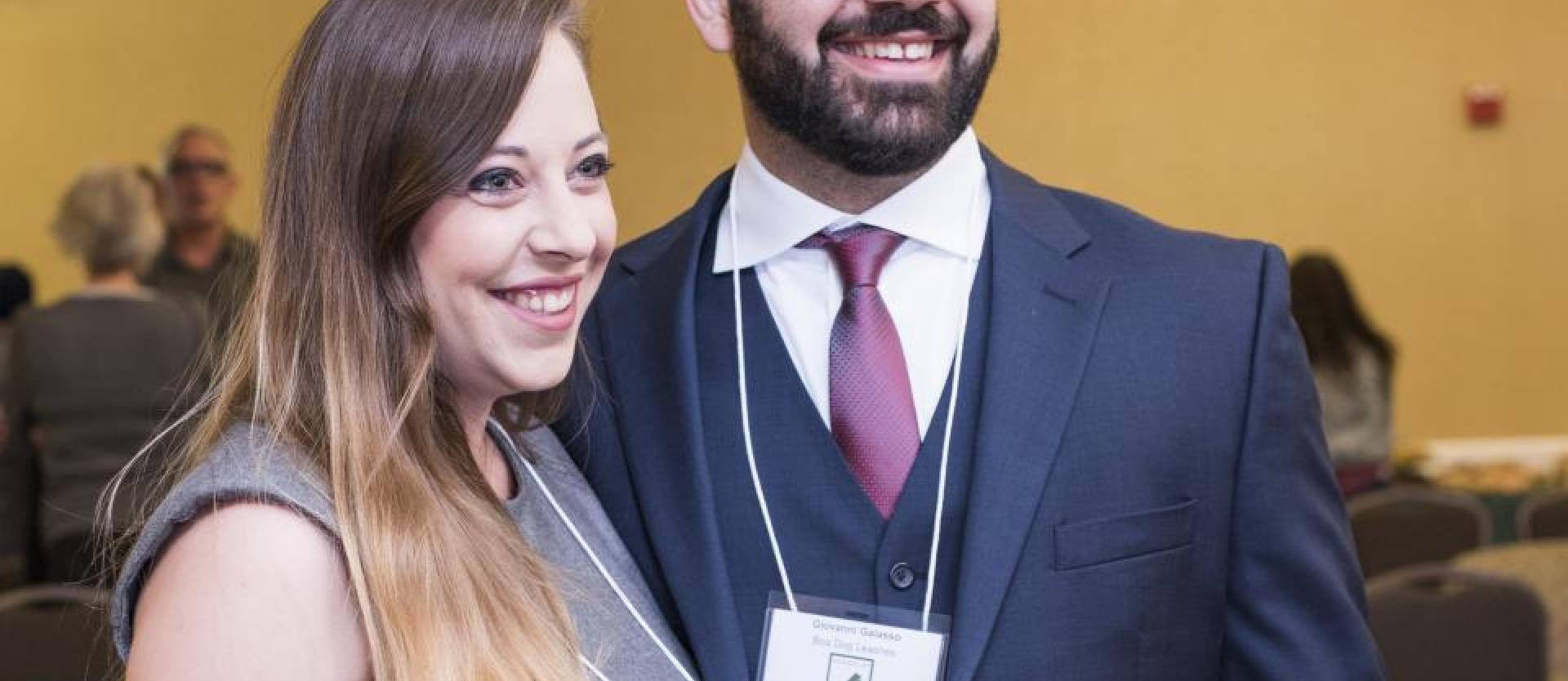 Two people in formal attire smiling for the camera looking to the right