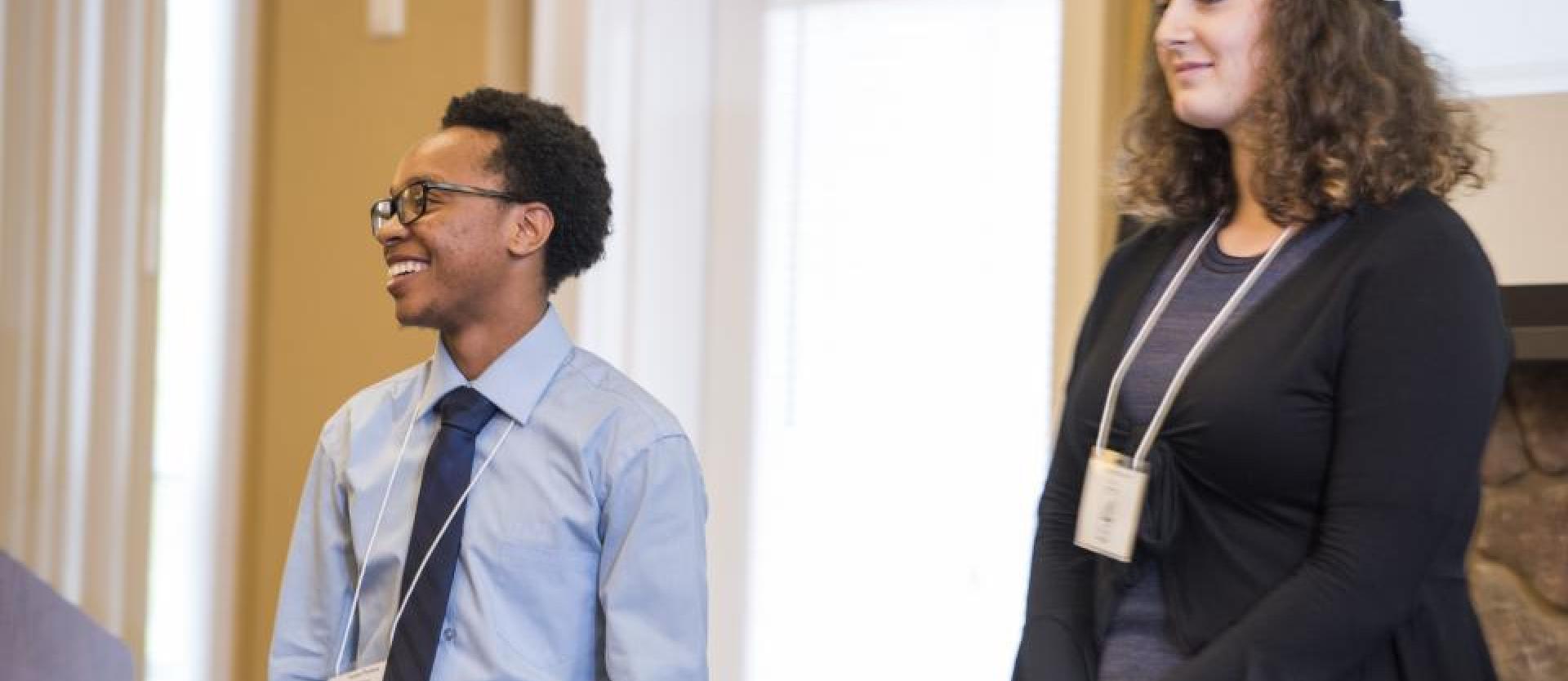 two student participants in formal attire standing in front of a door