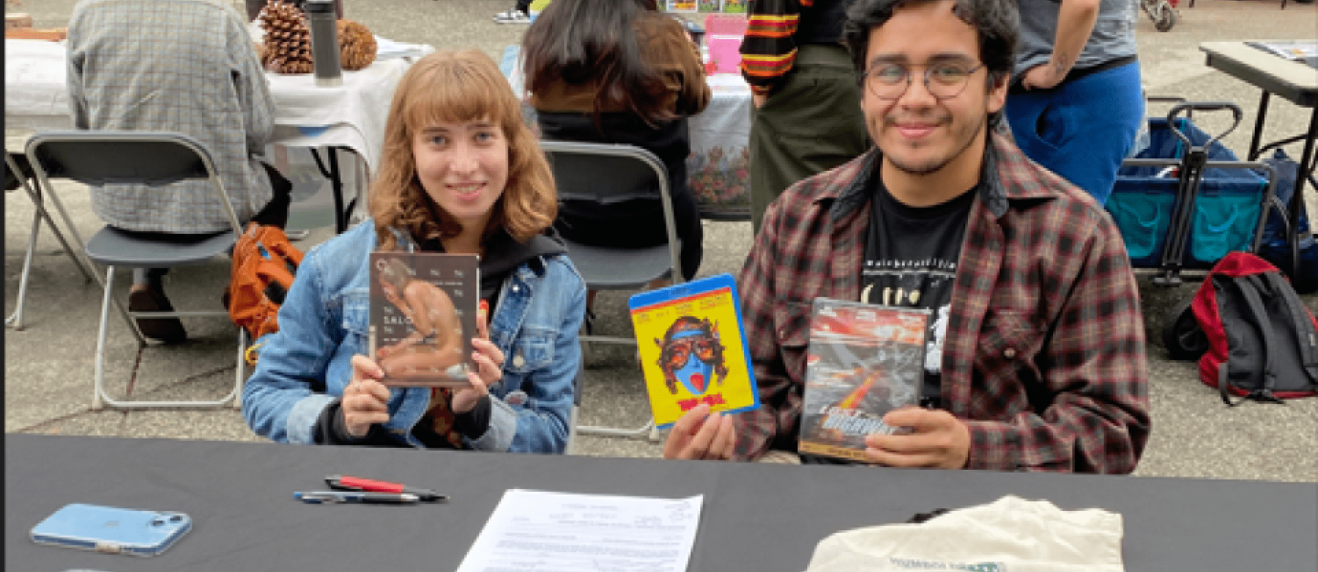 two students at a table holding movies/dvds