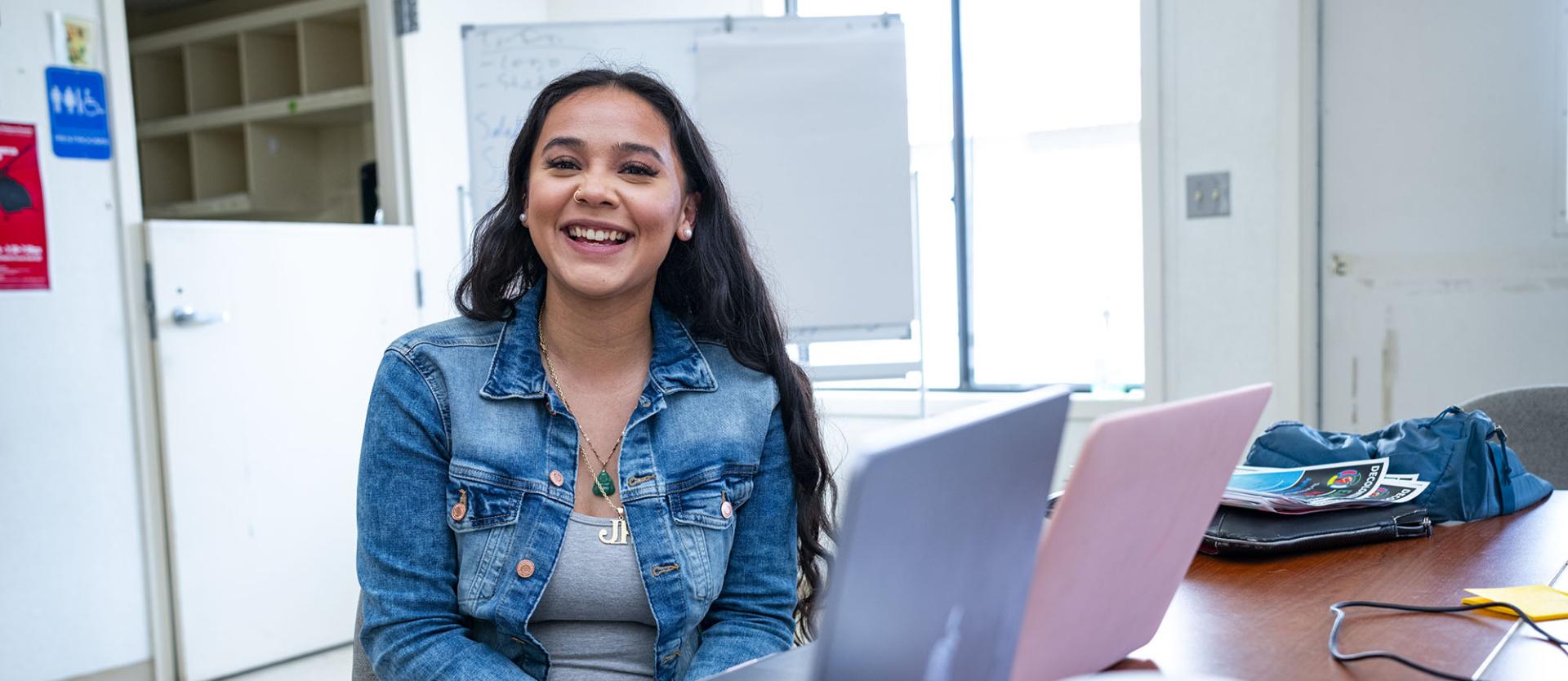 A female student in a classroom smiling