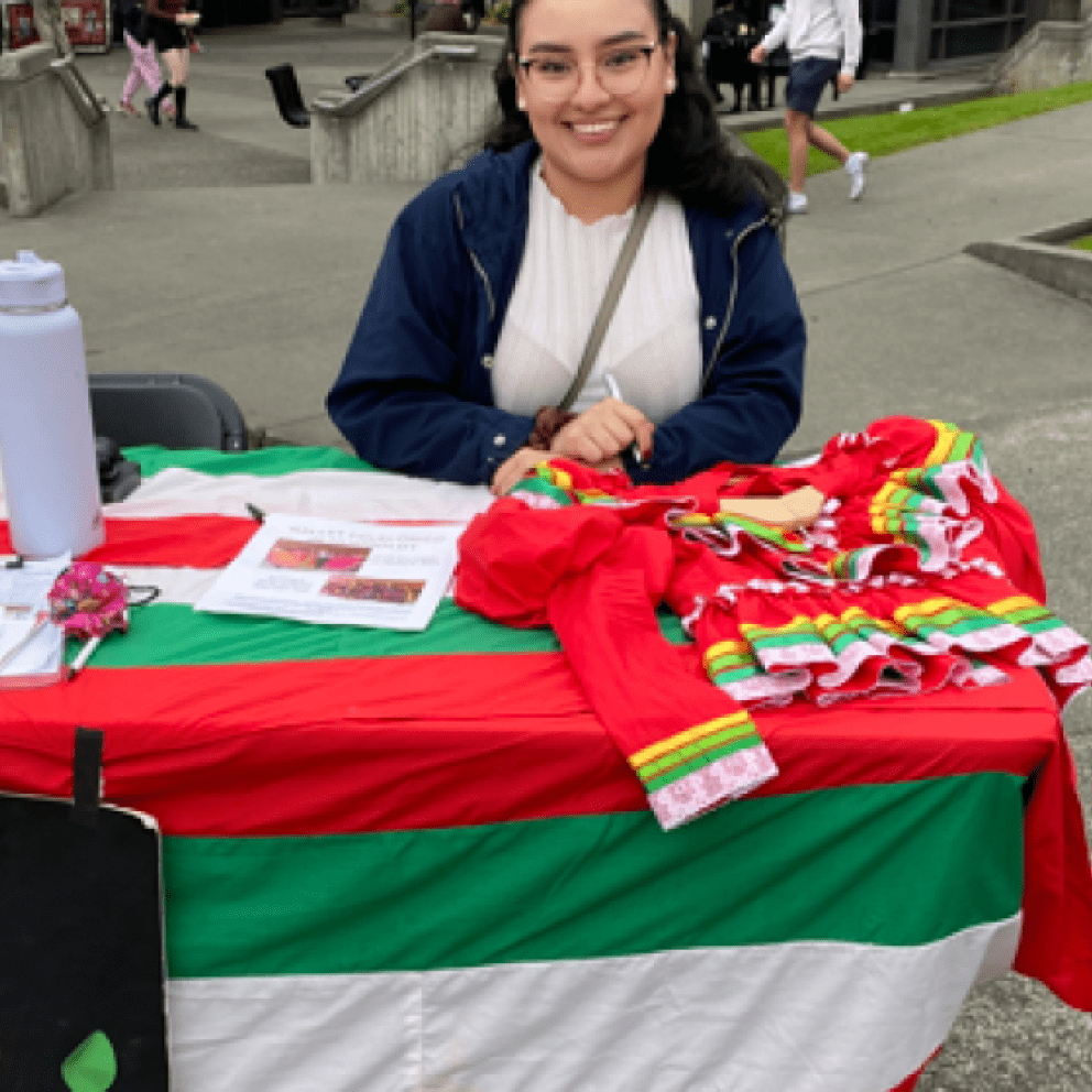 one student at a table with items from Ballet Folklorico de Humboldt