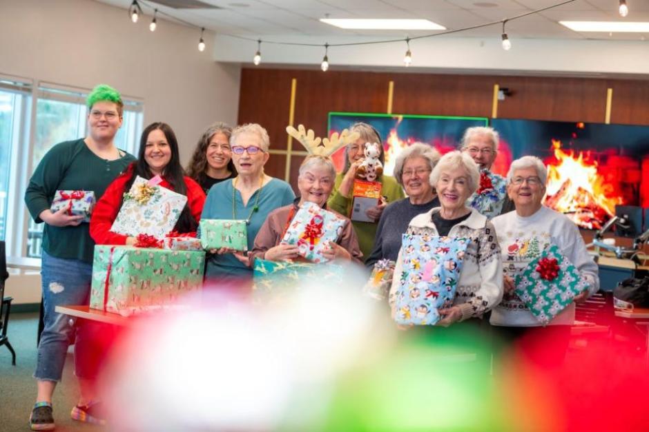 a group of people holding wrapped gifts and smiling 