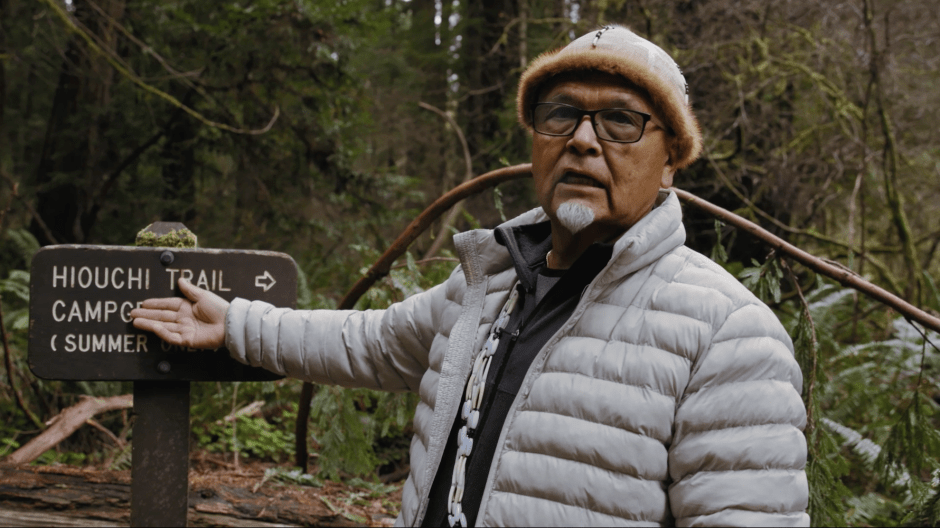 Loren Me_-lash-ne Bommelyn points toward sign that reads Huouchi trail. 