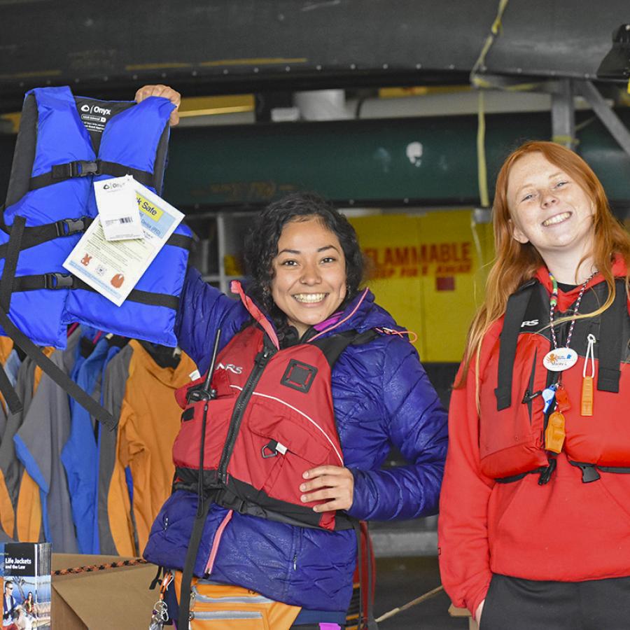 two people wearing and holding lifejackets