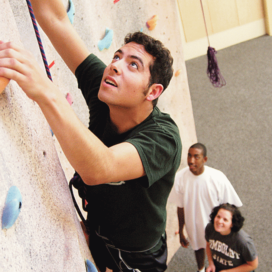 Man climbing on a rockwall with onlookers below