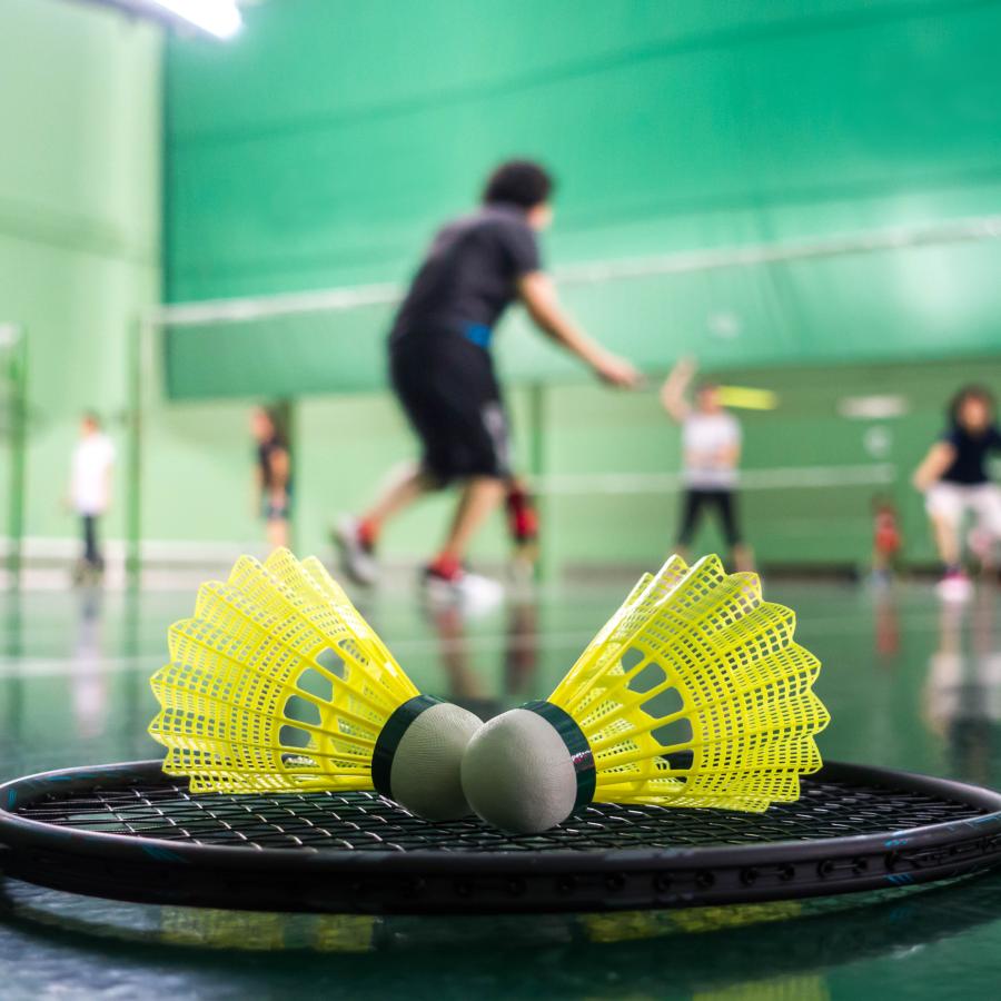 Several people playing badminton games, with racquet and shuttles in the foreground