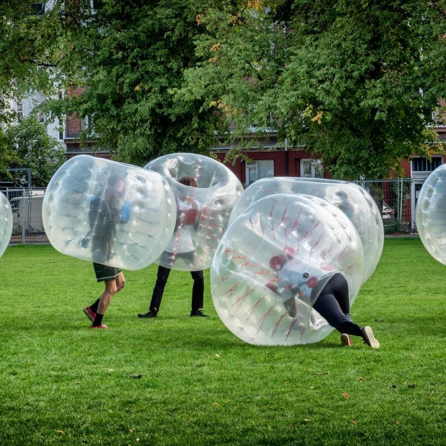 Small group of people playing soccer while wearing zorb balls