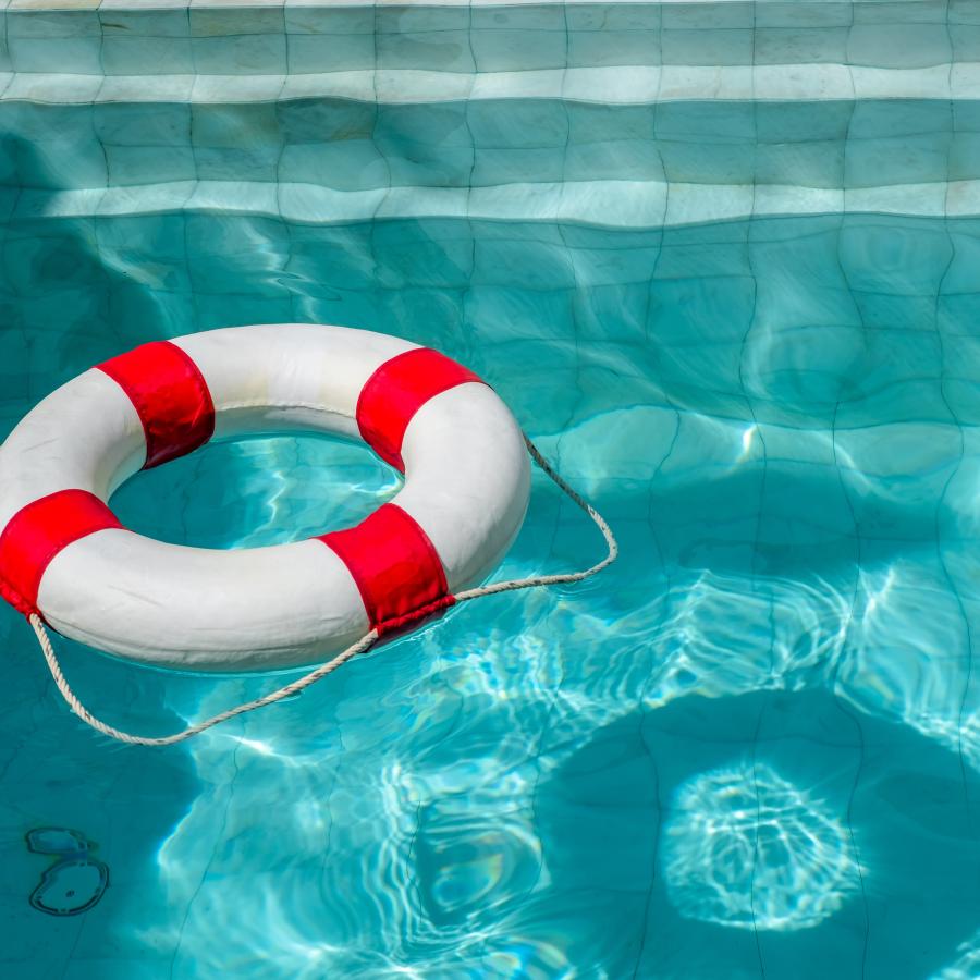 A red and white circular buoy floating in a pool of clear, light blue water