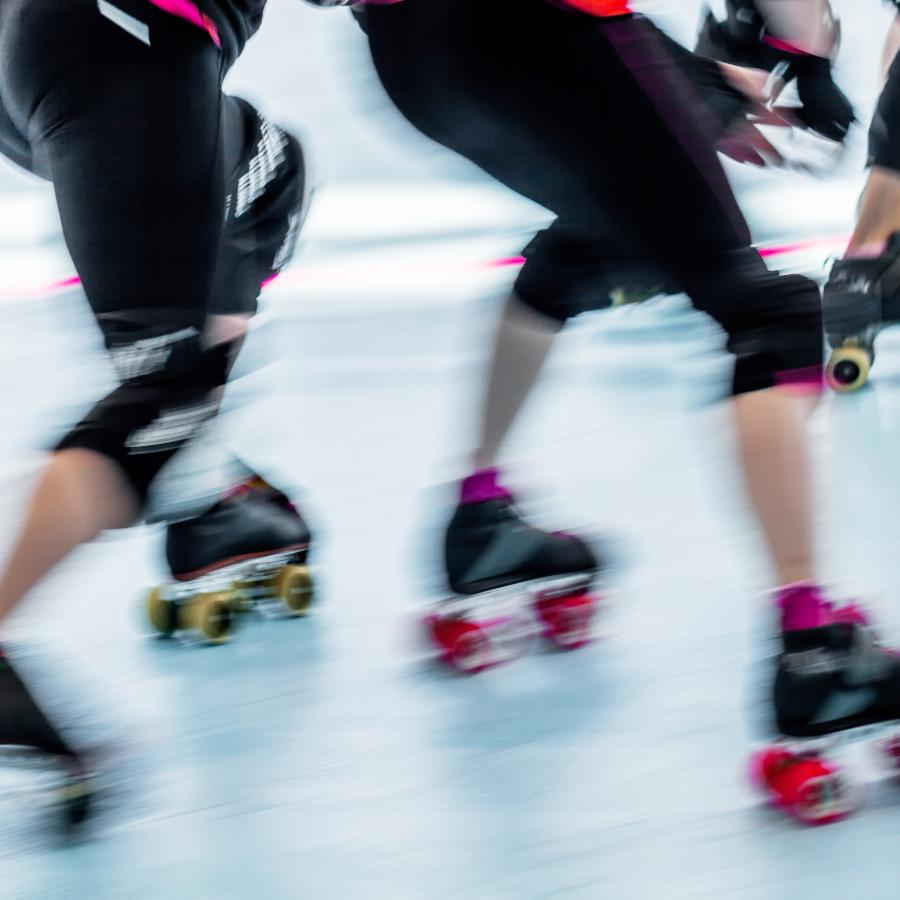 3 roller skaters in motion, the picture only shows their legs and their skates. They are blurred as if traveling at a very high rate of speed