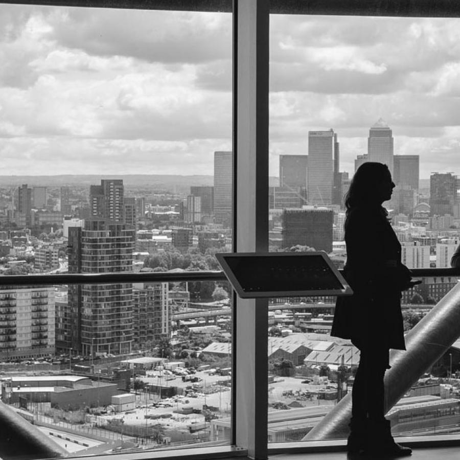 People inside a high-rise building, looking through large windows at a city