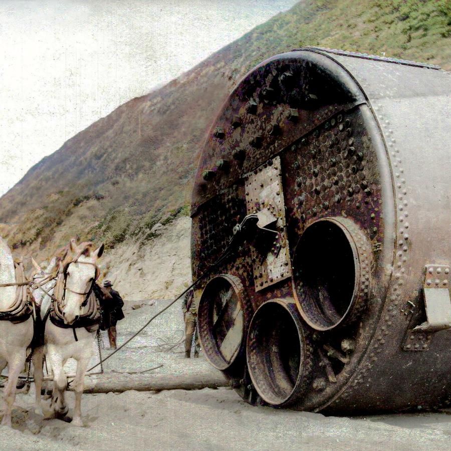 Historic image of horses pulling a large boiler on a dirt road