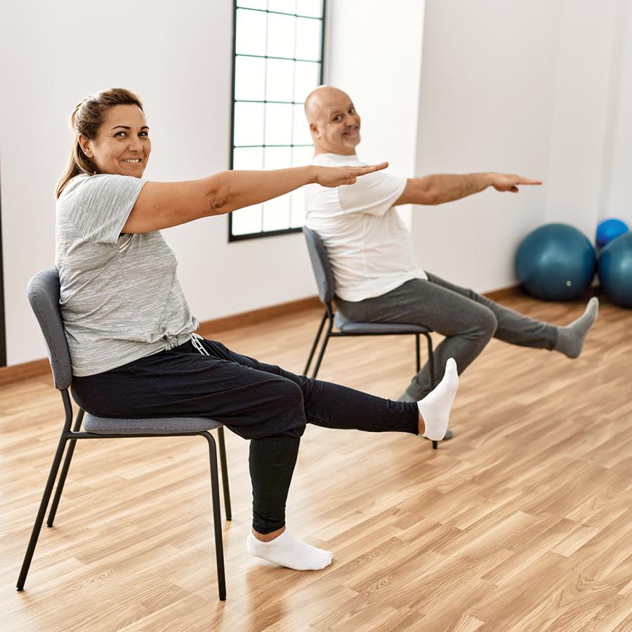 Two people in chairs, doing Pilates moves