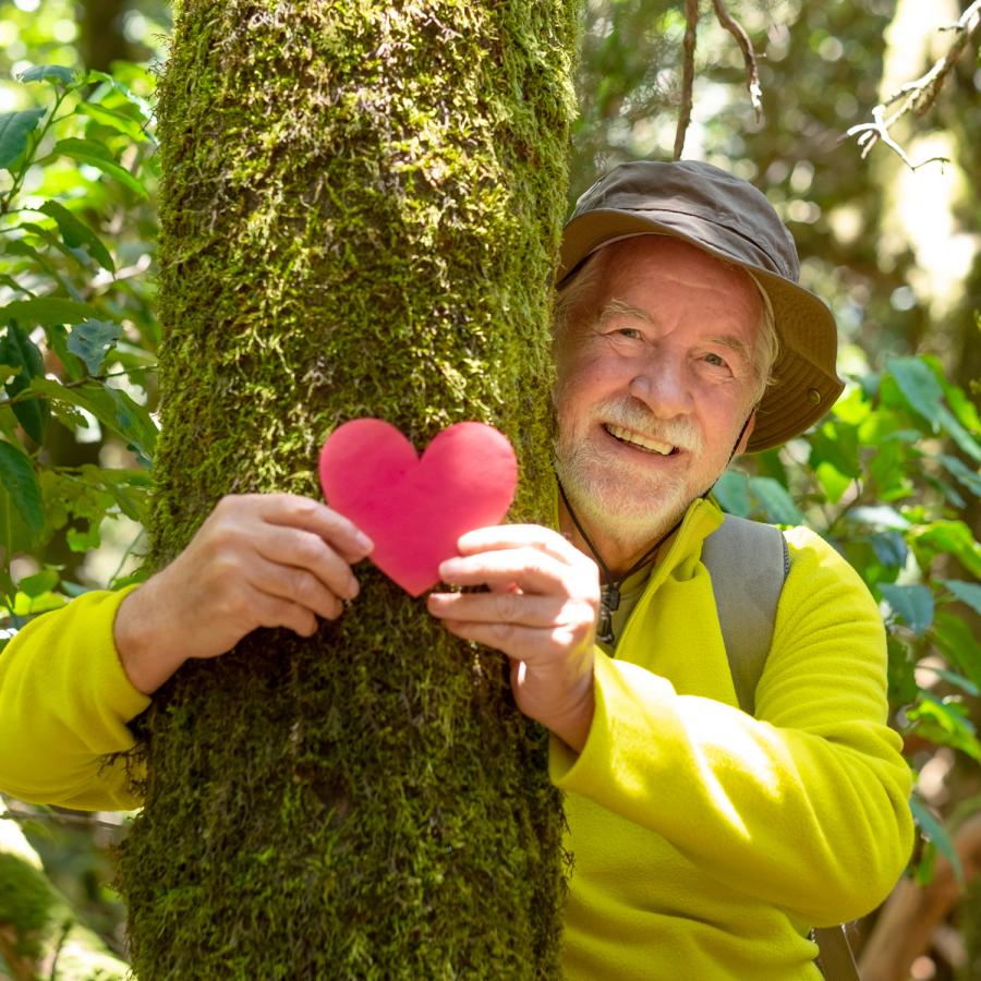 Man hugging a tree, and holding a paper heart