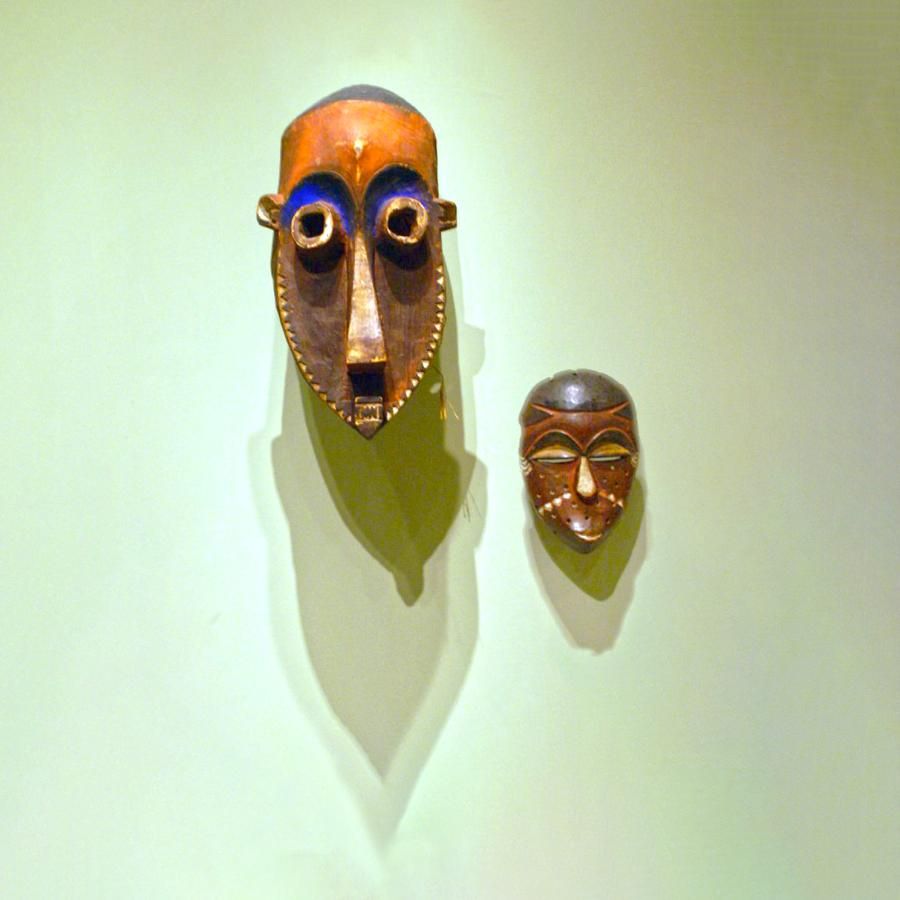 Two African masks hanging on a museum wall