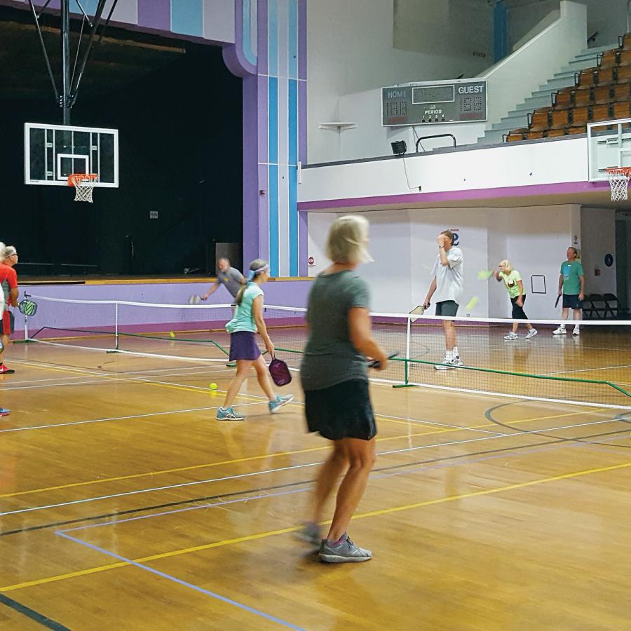 People playing pickleball in a basketball court