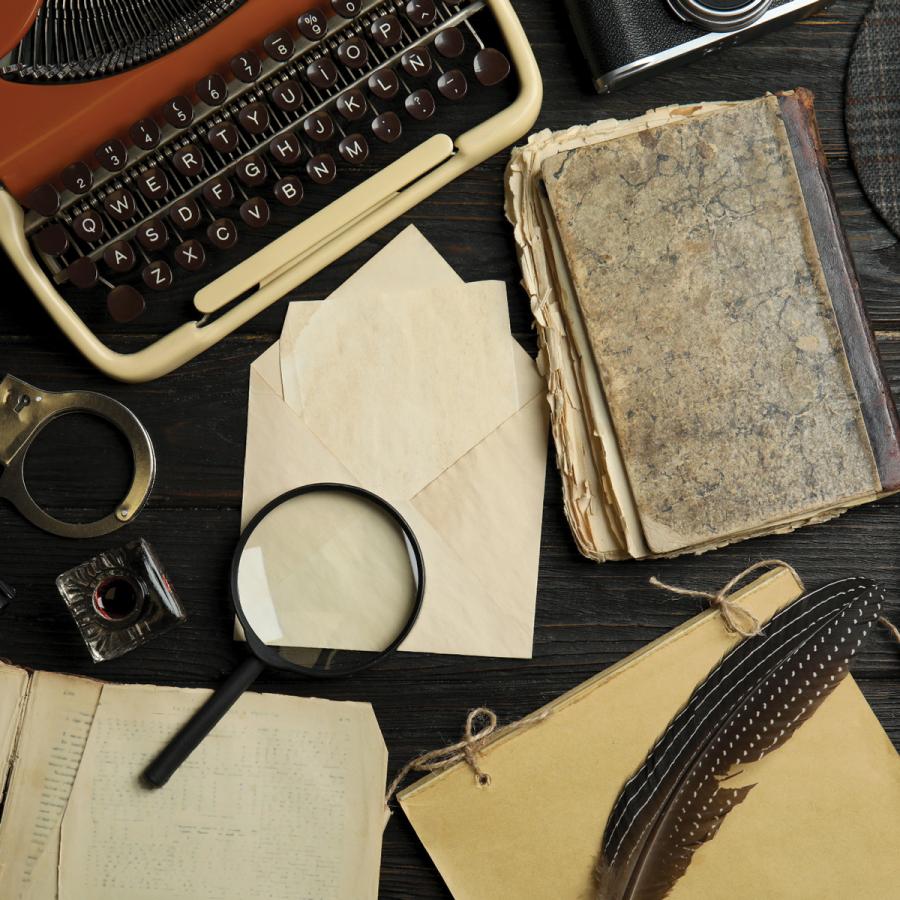 Detective's desktop with typewriter, magnifying glass, handcuffs, notebooks
