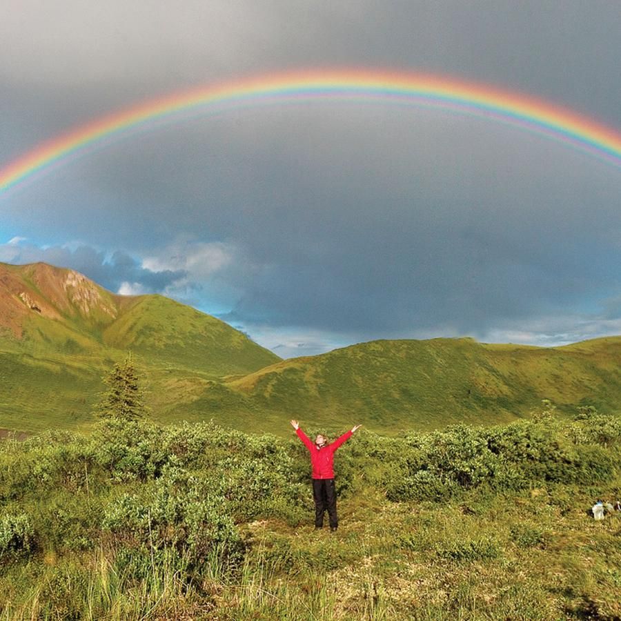 Rainbow above landscape with person on the ground Rainbow above landscape with person on the ground
