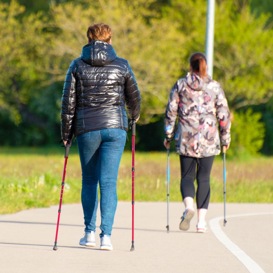 Two women using walking sticks on a trail. Two women using walking sticks on a trail.