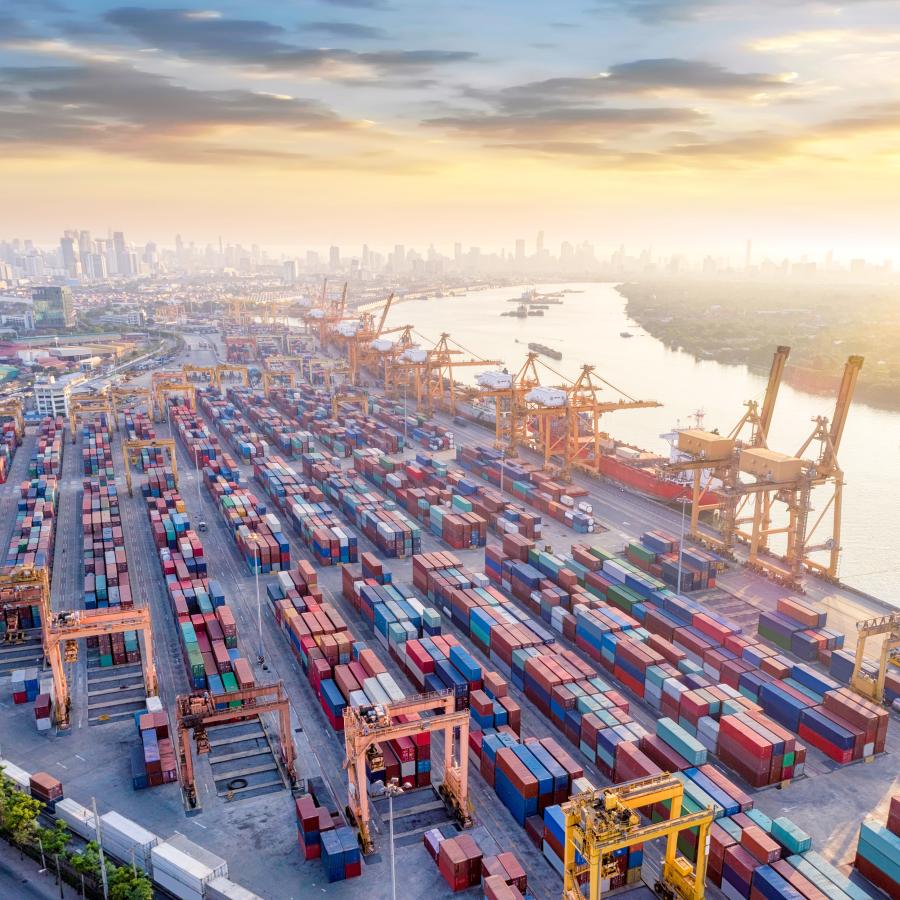 bustling commercial port terminal filled with hundreds of shipping containers and cranes, alongside a river bustling commercial port terminal filled with hundreds of shipping containers and cranes, alongside a river