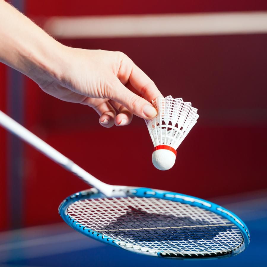 person serving the birdie with a badminton racket person serving the birdie with a badminton racket