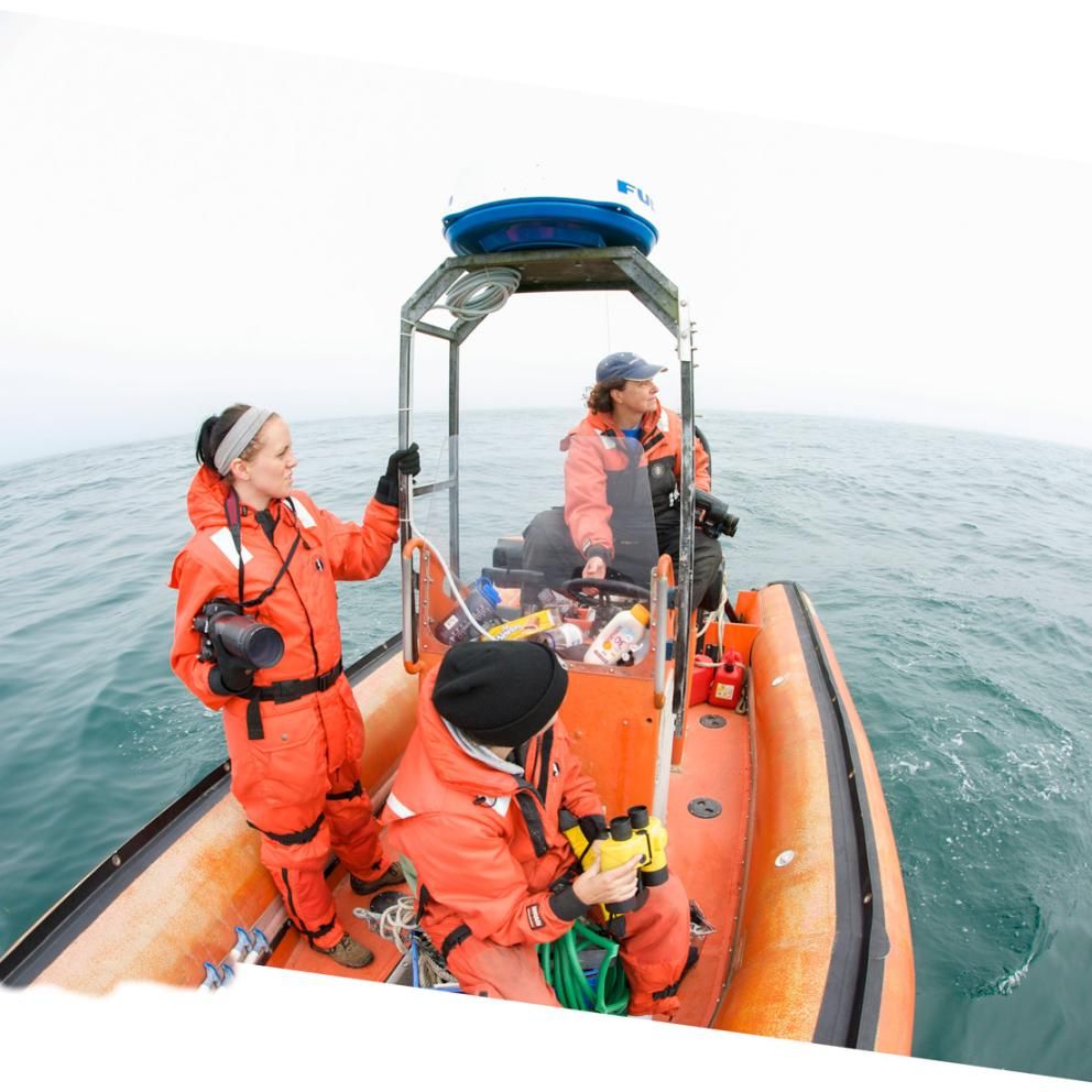 Students on a boat wearing orange waterproof outfits