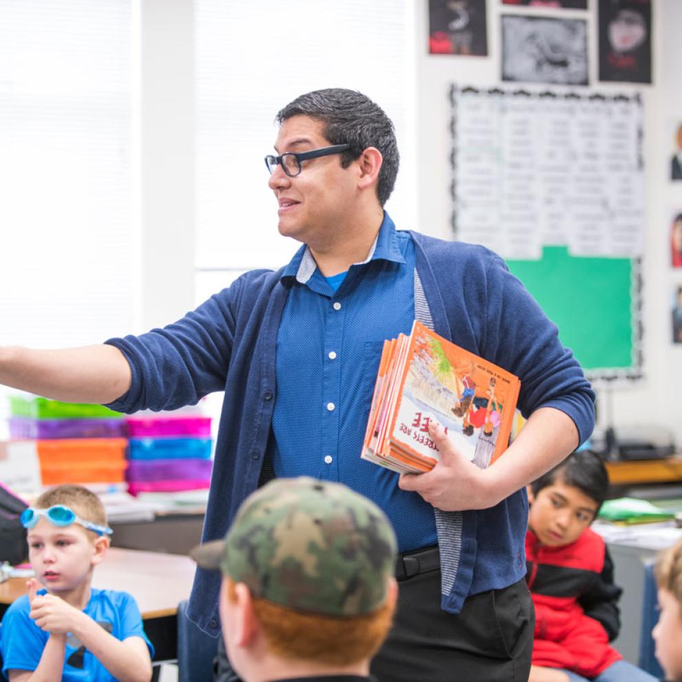 A student teacher holding some books talking to a class