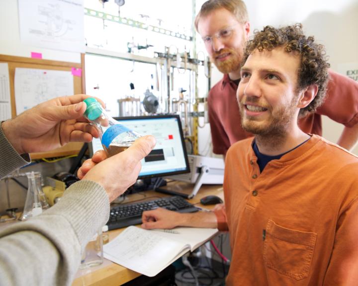 hands holding a specimen bottle presenting it to a student