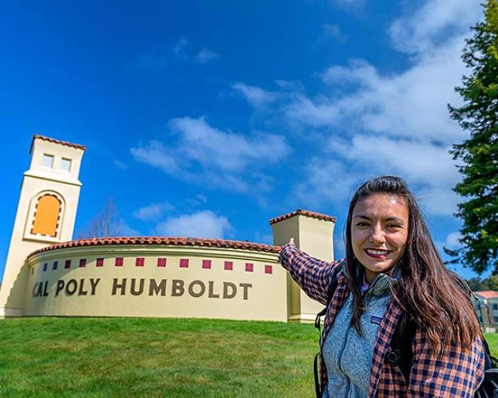 Student pointing at campus entrance