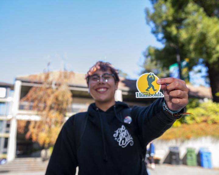 Someone holding up a sticker of Bigfoot making a heart