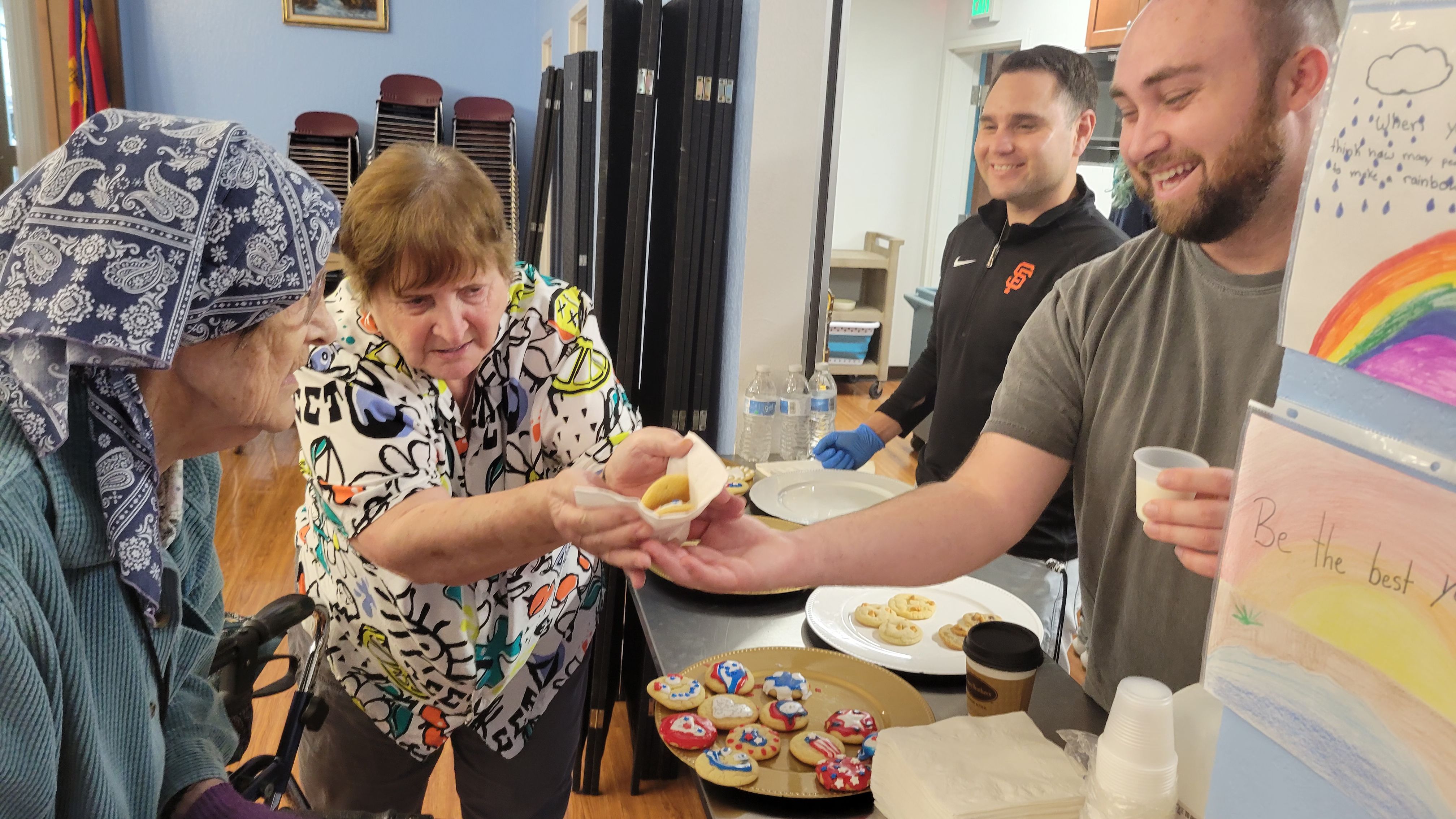 Eric Hansen and a volunteer serve baked goods to two residents at Silvercrest